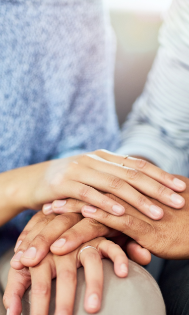 Close-up of two women's hands resting together on knees