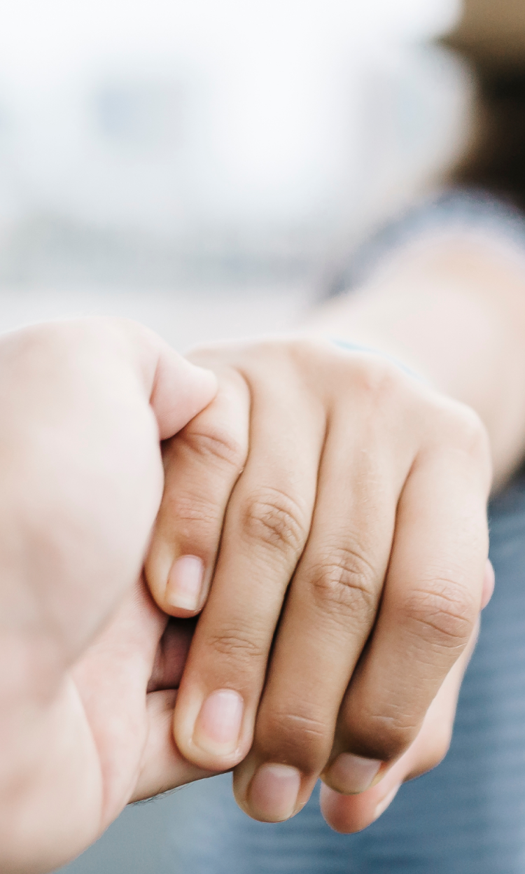 Close-up of man's hand holding onto female breast cancer patient's hand